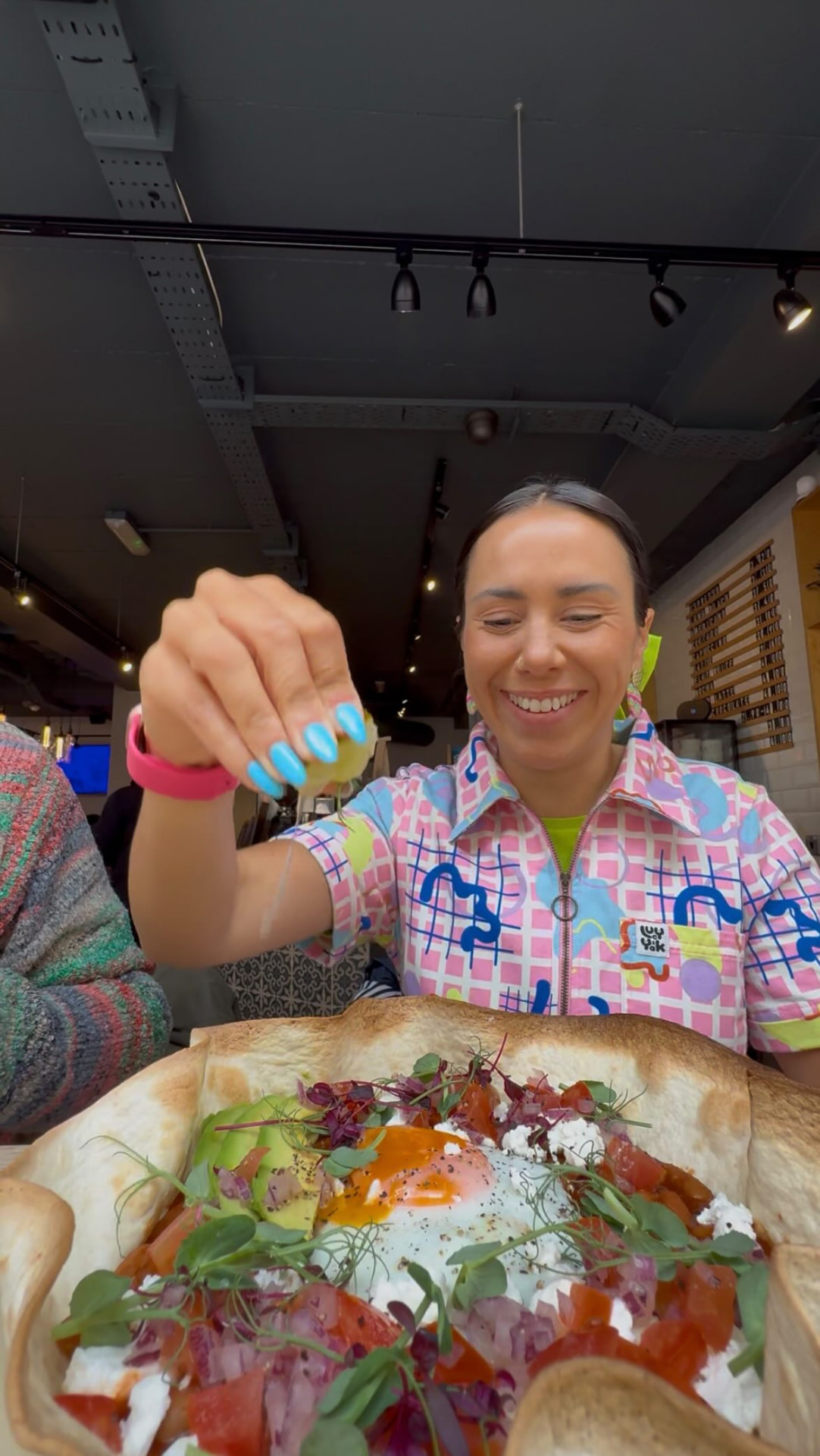 Guest squeezing lime over a baked eggs tortilla bowl