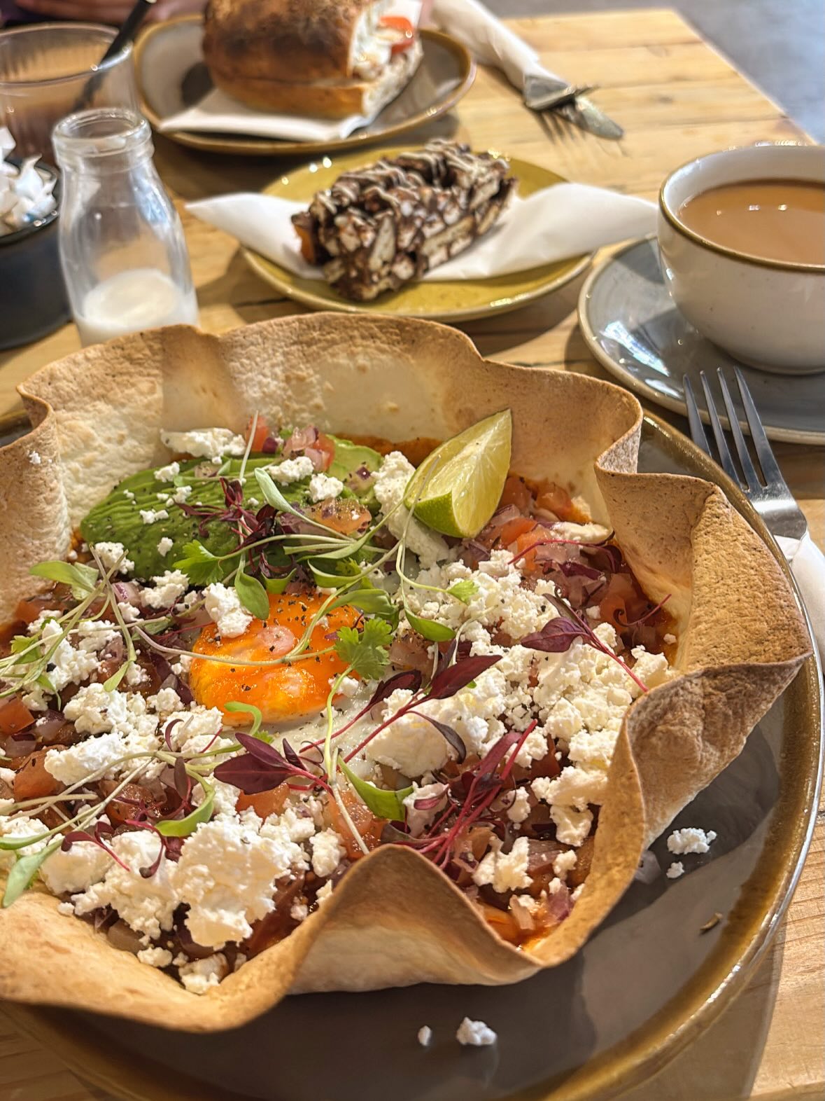 Baked eggs tortilla bowl with feta, avocado and micro herbs