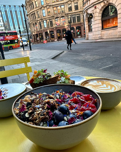 Brunch bowls and coffee on a yellow table outside on the street