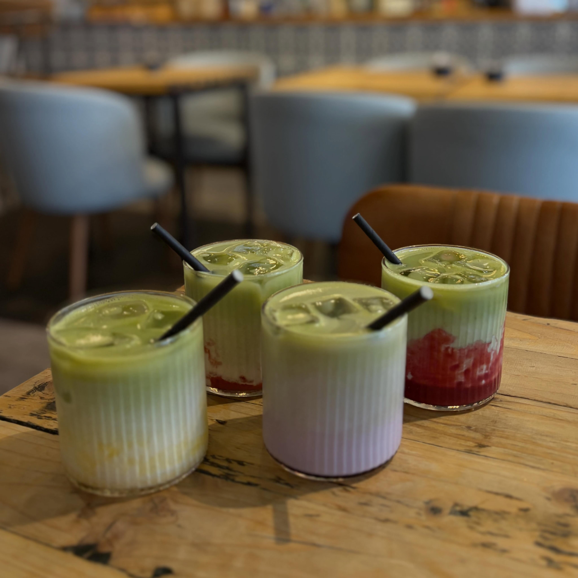 Four layered iced matcha drinks on a wooden table