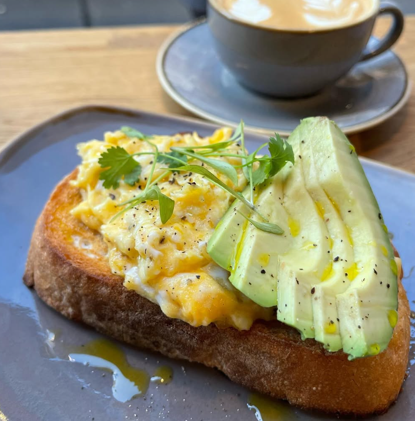 Scrambled eggs and avocado on sourdough with a flat white