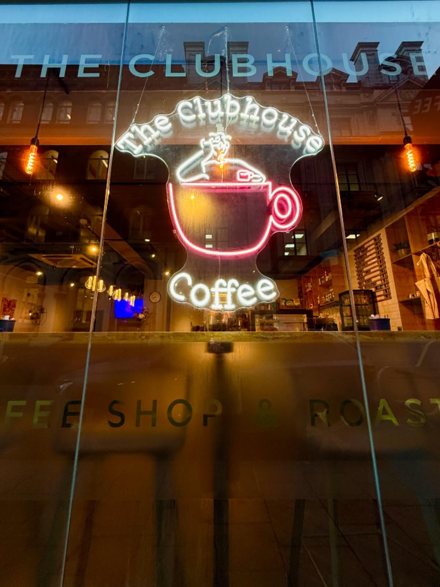 The Clubhouse neon coffee cup sign lit up at night