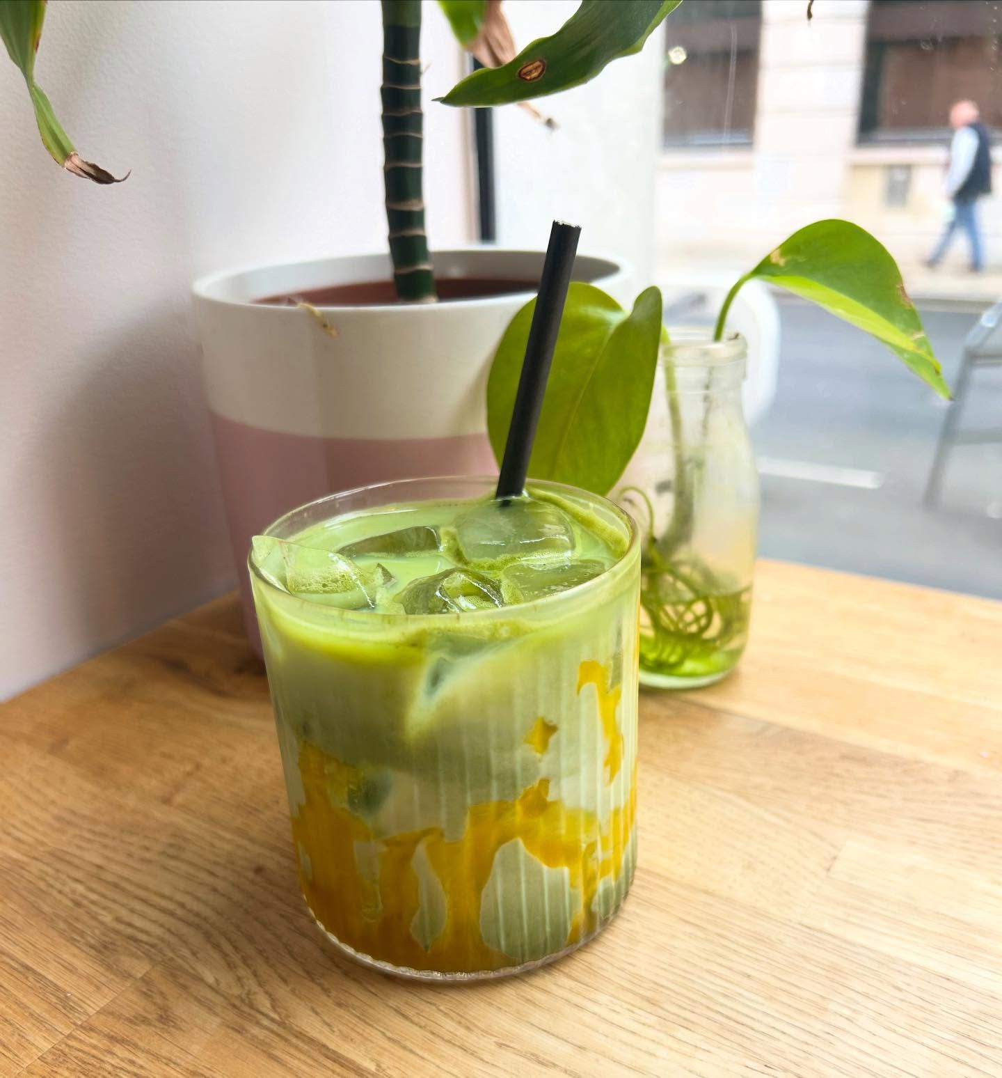 Iced mango matcha latte on a wooden table by the window