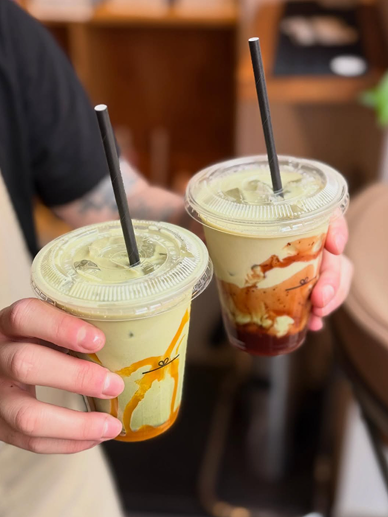 Two iced matcha drinks with mango and berry swirls