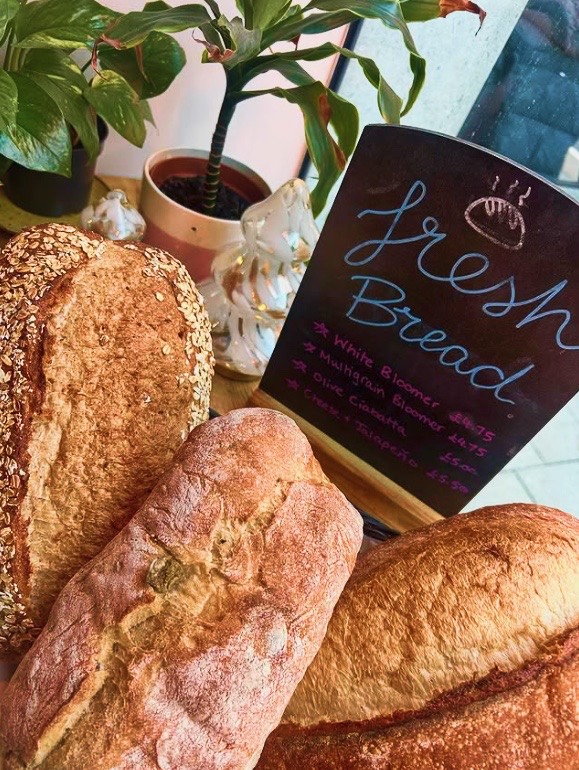 Fresh loaves of bread beside a chalkboard menu