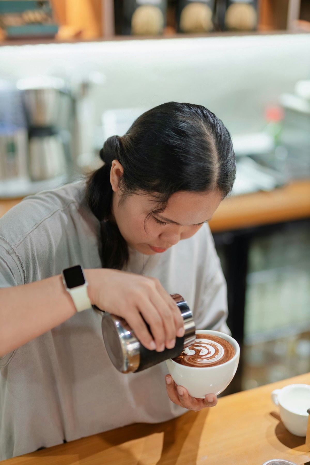 A barista pouring latte art into a cup