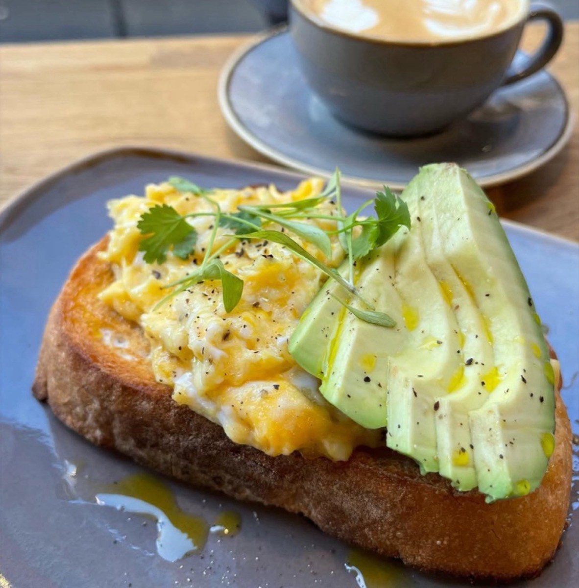 Scrambled eggs and avocado on sourdough with a flat white