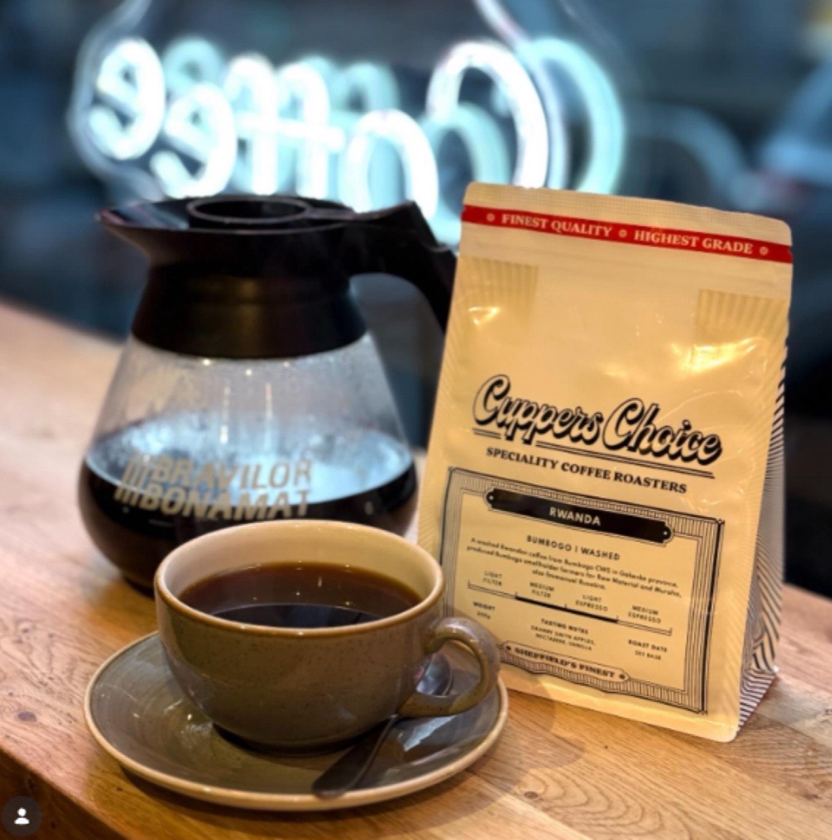 Filter coffee with a Cuppers Choice bag under a neon coffee sign